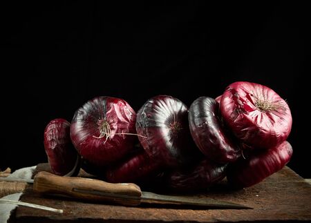 round red onion in husk on a gray linen napkin, black background, close upの写真素材
