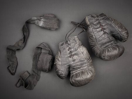 very old vintage leather black boxing gloves with laces and a black elastic bandage for rewinding, sports backdrop の写真素材