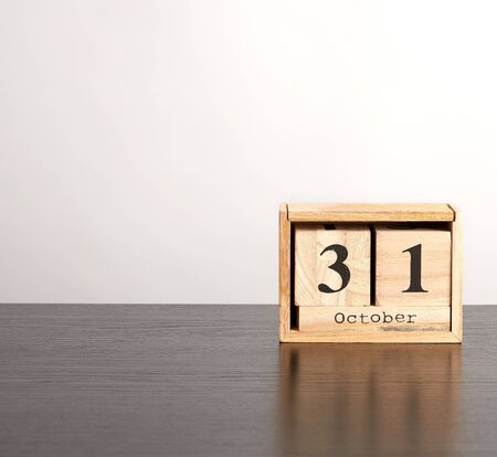 wooden calendar of cubes with the date October 31 on a black table, celebration of Halloween,...