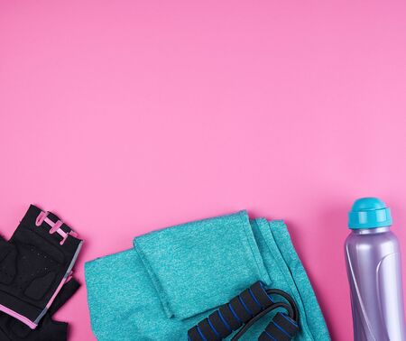 pink women's sneakers, bottle of water, gloves and a jump rope for sports on a pink background, top view, copy spaceの写真素材