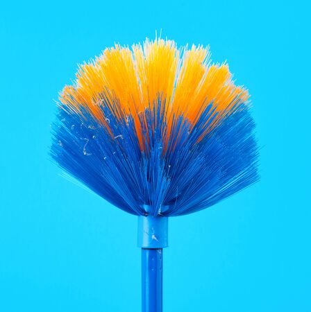 blue-yellow mop broom for collecting dust on a stick, blue backgroundの写真素材