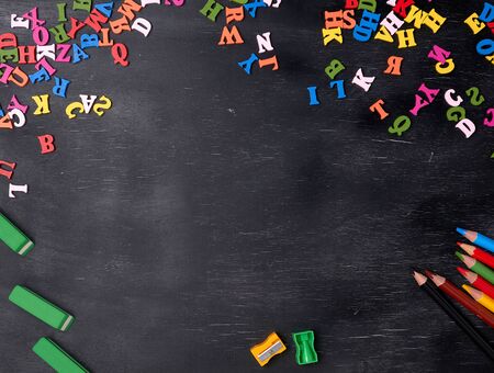 multicolored small wooden letters of the English alphabet on a black chalkboard, copy space, back to schoolの写真素材