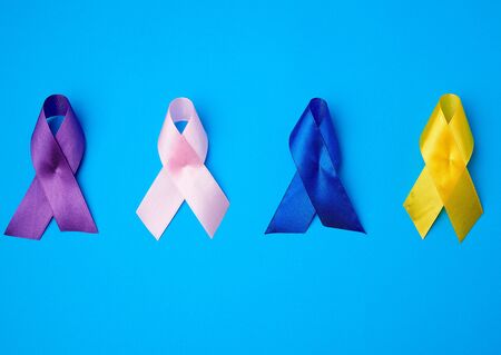 purple, yellow, blue, pink ribbon in the form of a bow, international symbols of diseases on a blue backgroundの写真素材