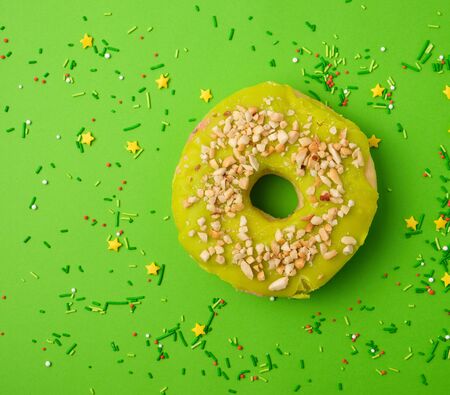 round sweet green pistachio donut sprinkled with ground nut on a green background, top viewの写真素材