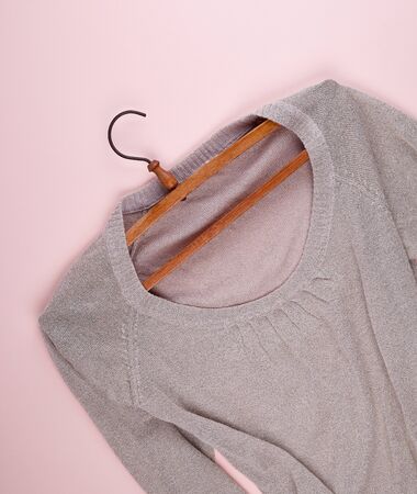 beige female sweater hanging on a vintage wooden hanger, beige backgroundの写真素材