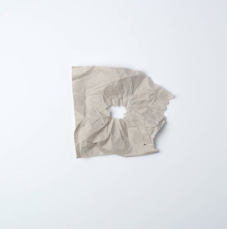 gray crumpled sheet of paper with a hole, white backing, abstract backgroundの写真素材