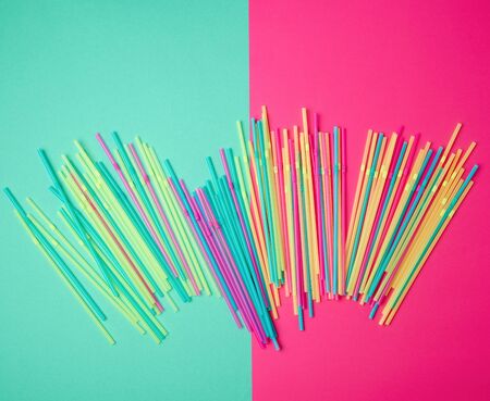 stack of multi-colored plastic tubes for a cocktail on a multi-colored background,  concept of environmental pollution by objects that decay in the ground for a long time, top viewの写真素材
