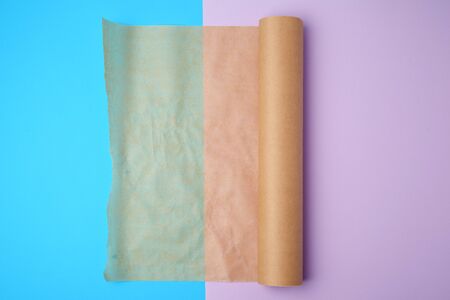 unwrapped a roll of brown parchment paper on a colored background, place for textの写真素材