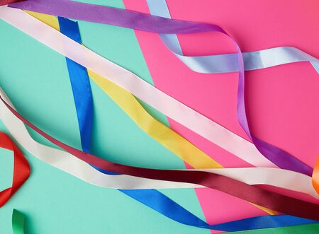 many silk multi-colored ribbons on a colored background, top viewの写真素材