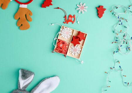 burning christmas garland on a white wire with colorful lights and box with wooden toys for the Christmas tree on a green background, copy spaceの写真素材