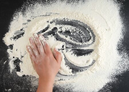 white wheat flour scattered on a black background, product is spread over the surface, kitchen background, top viewの写真素材