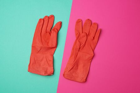 pair of rubber orange gloves for cleaning the house on a colored background, flat layの写真素材