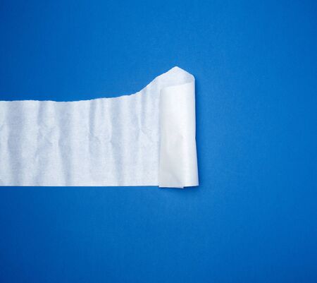torn and twisted piece of white paper on a blue background, close up