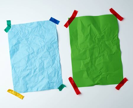 two blank crumpled sheets of paper glued with rubber colored adhesive tape on a white background,...