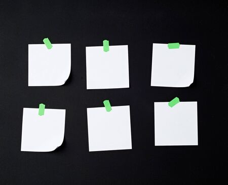 set of square white blank sheets of paper glued with green sticky paper on black backgroundの写真素材
