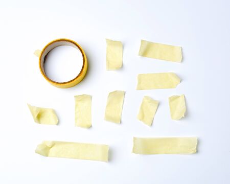 set of various pieces of yellow sticky paper tape on a white background, close up