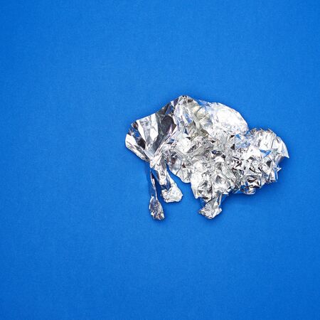 piece of crumpled foil on a blue background, close upの写真素材