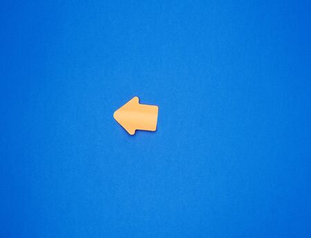 orange paper sticker in the form of an arrow pointer is glued on a blue background, place for an inscriptionの写真素材