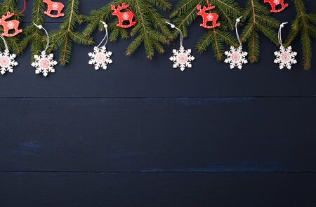 green branches of spruce, decorative wooden toys on a blue background from parallel wooden boards,...
