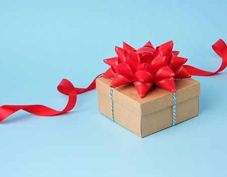 closed blue cardboard gift square box tied white trope on a blue background, top view, holiday background の写真素材