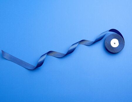 twisted dark blue silk ribbon on a blue background, element for the designerの写真素材