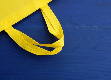 Reusable yellow viscose bag on blue wooden background, plastic waste reduction conceptの写真素材