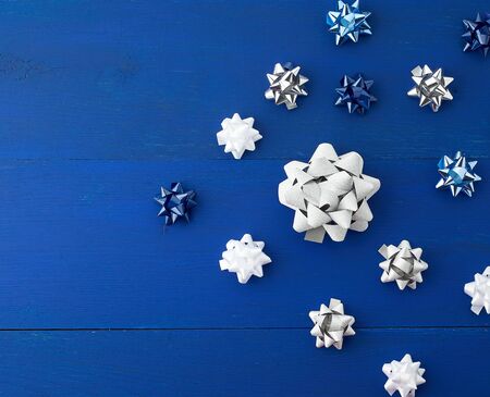 related white, blue and gray bows for gifts on a blue wooden background, decor for decorating gifts,...