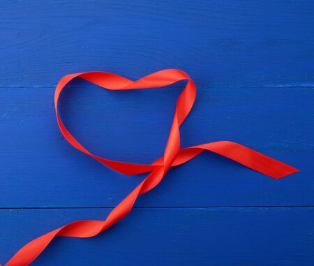 twisted silk ribbon on a blue wooden background, abstract holiday backdropの写真素材
