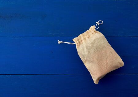 small full canvas bag with ties, blue wooden background, top view. Reusable eco bag.の写真素材