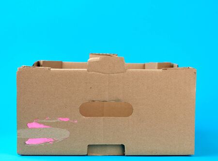 rectangular empty cardboard box of brown paper on a blue background, box without a lid for...
