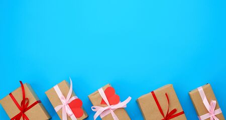 box is wrapped in brown paper and tied with a red thin silk ribbon on a blue background, red cut out...