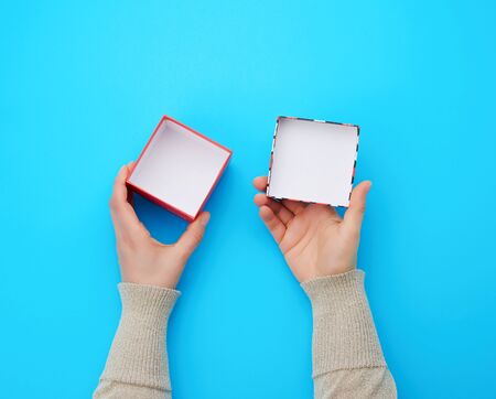 girl opens a brown square box on a blue background, top view, concept of giving gifts