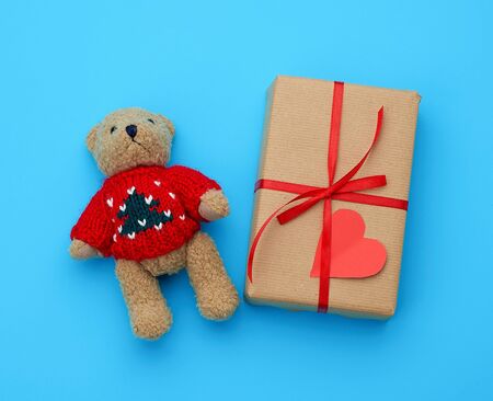 brown gift box and little brown teddy bear on a blue background, top viewの写真素材