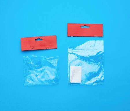 two transparent torn plastic bags with paper red top for packaging goods, blue background