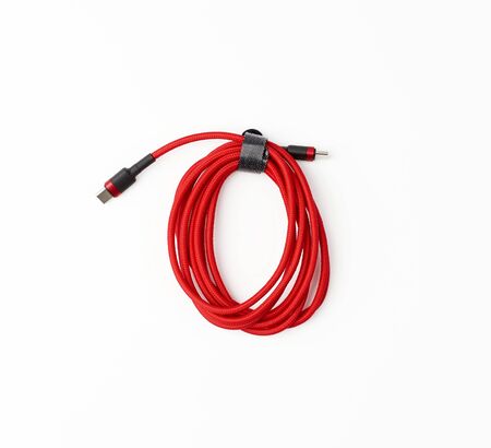 twisted cable for charging mobile devices in a red textile wrapper on a white backgroundの写真素材