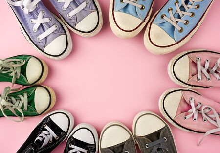 many multi-colored well-worn textile sneakers of different sizes on a pink background, top view, concept, family and team, friendship, copy spaceの写真素材