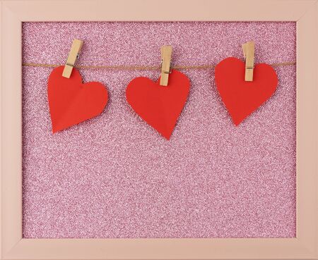 carved red paper hearts hanging on a brown rope, pink shiny background, valentines day cardの写真素材