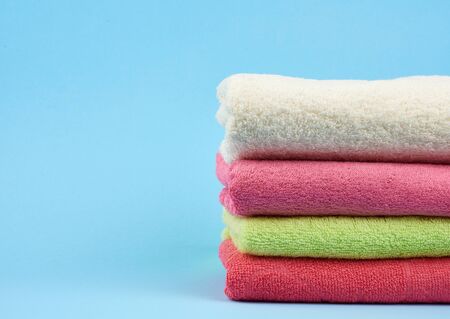stack of colored cotton terry folded towels on a blue background, copy spaceの写真素材