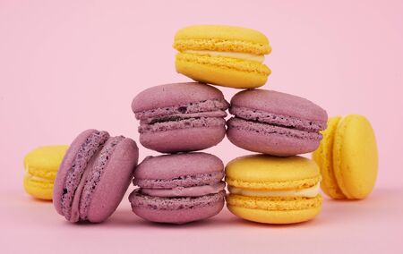 yellow in purple round baked macaroon cakes on a pink background, dessert stands in a stack, deliciousの写真素材