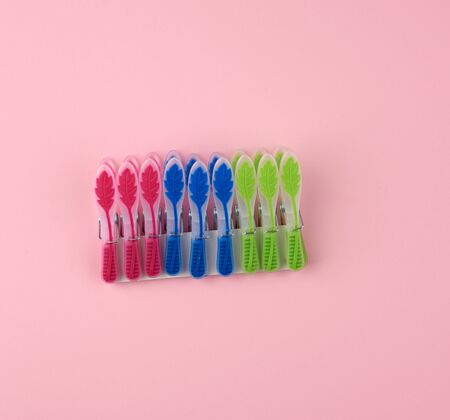 plastic multi-colored clothespins on a pink background, top view