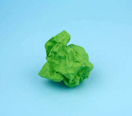 crumpled sheet of green paper on a blue background, close up