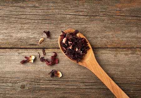 dry petals of red hibiscus in a wooden spoon, tea preparation, top viewの写真素材
