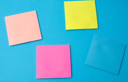 multicolored blank paper stickers of different colors on a blue background, copy spaceの写真素材