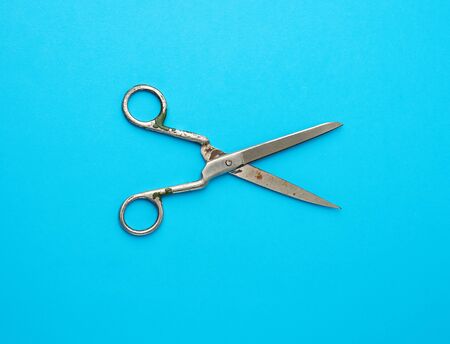very old vintage metal tailor scissors on a blue background, close up