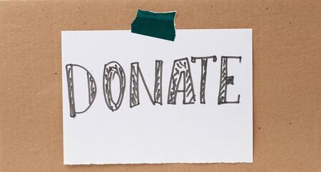 inscription donate on a white sheet and glued brown cardboard paper, concept of volunteering and promotionの写真素材