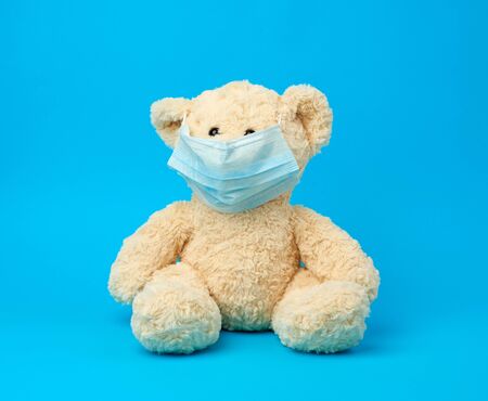 big teddy bear are sitting in medical masks on a blue background, concept of protection from...