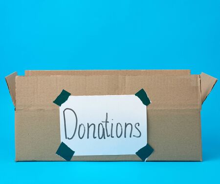 brown cardboard box with a pasted white sheet and the inscription donations on a blue background,...