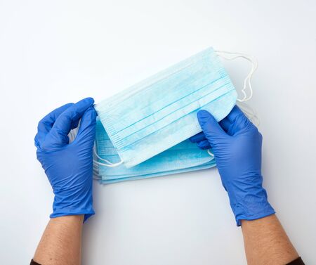 hands holds a medical face medical mask against viruses and bacteria on a white background,...