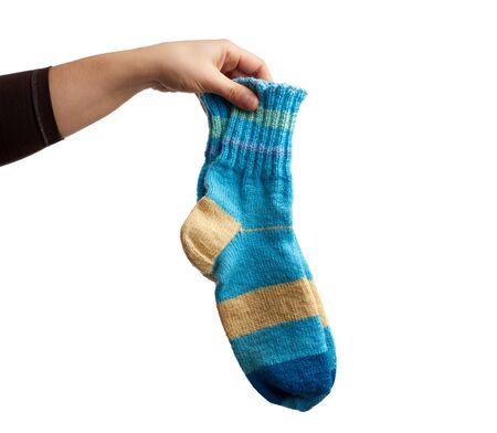 female hand holds a pair of knitted woolen socks, warm clothes, item is isolated on a white background の写真素材
