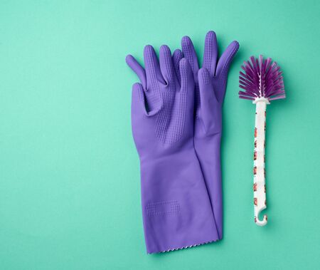 purple rubber gloves for cleaning and a white brush on a green background, flat layの写真素材